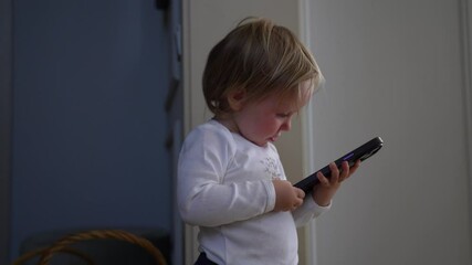 Toddler is captivated by a smartphone, engrossed in the screen and digital world, exploring and learning