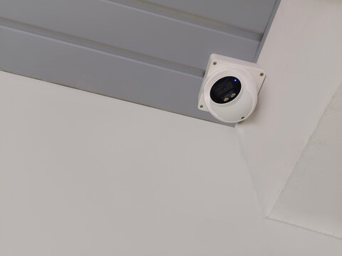 Black and white CCTV camera mounted on a grey roof and white wall background, object, technology, care, decor, copy space.jpg
