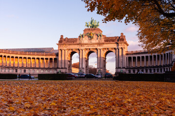 Low angle view of the Cinquantenaire Arcade at sunset in autumn, with fallen leaves covering the foreground