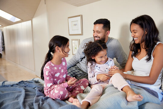 Happy mixed race family playing together in bed