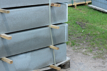 Stacked concrete curbs for sidewalk with wooden spacers, ready for installation at construction site