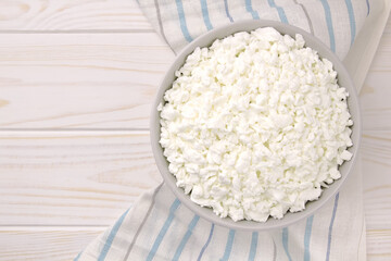Farm cheese in a bowl on a light wooden background.