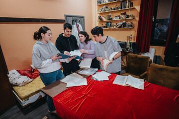 Four young actors collaborate on their scripts in a theater setting, actively studying and...