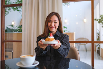 Portrait image of a woman holding and serving a plate of strawberry choux cream