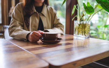 Closeup image of a woman holding a cup of hot coffee in cafe
