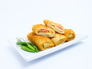 Indonesian risoles filled with vegetables, served with fresh green chilies on a white plate. Crispy breadcrumb coating on white background
