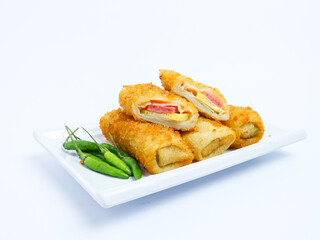 Indonesian risoles filled with vegetables, served with fresh green chilies on a white plate. Crispy breadcrumb coating on white background