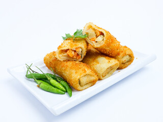 Indonesian risoles filled with vegetables, served with fresh green chilies on a white plate. Crispy breadcrumb coating on white background