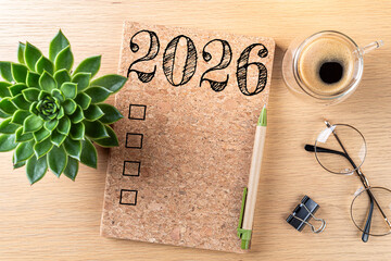 New year resolutions 2026 on desk. 2026 goals list with notebook, coffee cup, plant on wooden table. Resolutions, plan, goals, action, checklist, idea concept. New Year 2026 resolutions, copy space