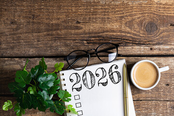 New year resolutions 2026 on desk. 2026 goals list with notebook, coffee cup, plant on wooden table. Resolutions, plan, goals, action, checklist, idea concept. New Year 2026 resolutions, copy space