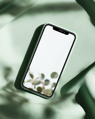 A modern smartphone with a clean white screen is artfully staged amidst verdant leaves and dappled shadows, creating a refreshing and organic composition.