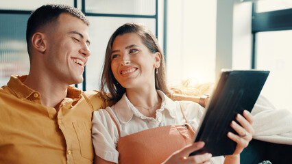 Happy, couple and relax with tablet at house for social media, browsing internet and bonding....