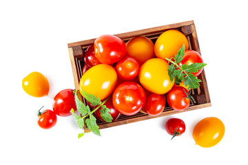 Ripe juicy yellow and red tomatoes with leaves in a wooden box.
