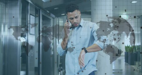 Man making phone call checking smartwatch for business meeting with world map overlay around him - Powered by Adobe