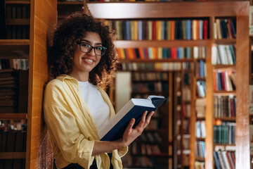 Leaning on the shelf. Beautiful woman is in the library
