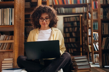 Sitting with laptop. Beautiful woman is in the library