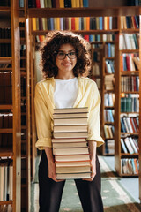 That's a lot of books in hands. Beautiful woman is in the library