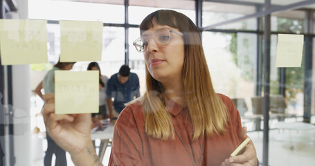 Office, businesswoman and writing on glass wall for sticky note, strategy and idea for creative...