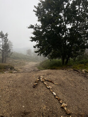  arrow made of rocks on the path through a foggy landscape in the woods on the pilgrimage along the road to Santiago in Portugal