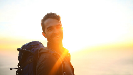 Hiking, sunrise and man with portrait outdoor for travel adventure, sightseeing or explore nature. Space, flare and person with backpack for trekking break, backpacker journey or happy at destination