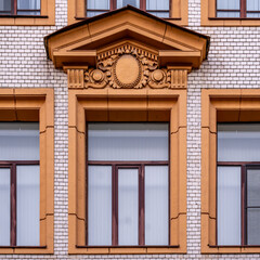 The wall of an old brick mansion with a large window.