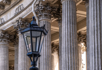 An antique lantern on a pillar against a background of columns.