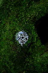 amulet with pentagram on green moss close up, abstract forest background. spiritual ritual. magic, witchcraft, pagan traditions, wiccan practice. esoteric symbol of pentacle. top view. copy space