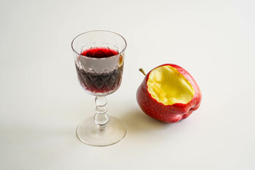 A glass of red wine and an apple core.