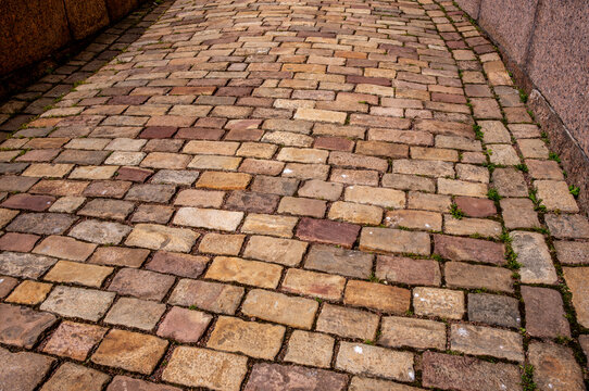 Fototapeta The pavement is made of cobblestones of different colors. Stone road.