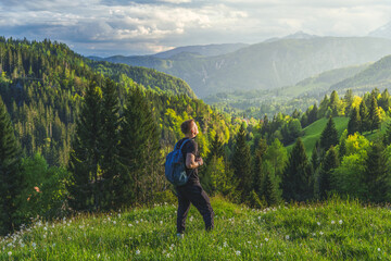 Man with backpack enjoying view of Slovenian Alps in Triglav National Park during scenic mountain hike