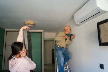 Elderly man and young woman doing DIY together at home