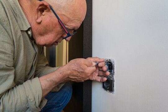 Elderly man engaged in DIY electrical repair at home
