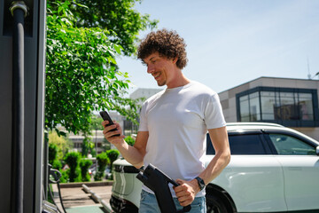 Man charging electric vehicle using smartphone