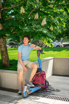 Man sitting with electric scooter under tree shade