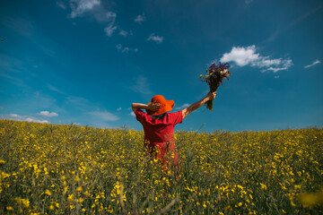 Trendy woman with stylish hat feeling free in the field with flowers