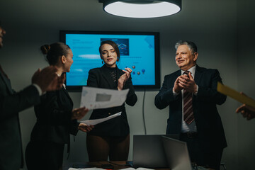 Business colleagues joyfully clapping and congratulating a team leader after a successful...