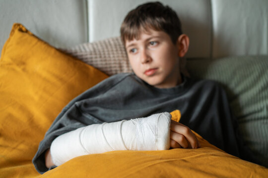Boy resting with arm in cast on colorful pillows
