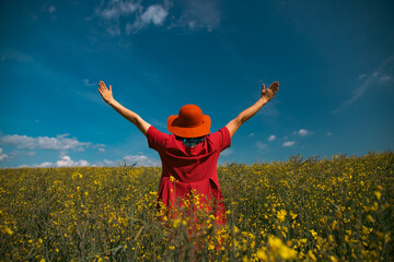 Trendy woman with stylish hat feeling free in the field with flowers