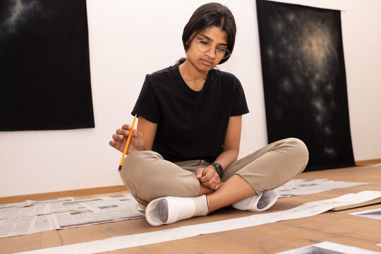 Young indian artist sitting and contemplating art piece