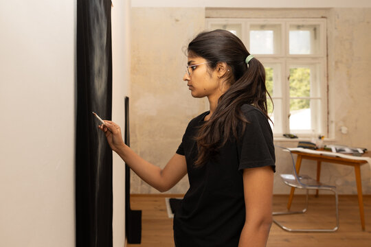 Young indian woman painting on canvas in art studio