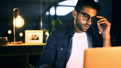 Man, glasses and laptop in office at night for planning, creative ideas and proofreading article....
