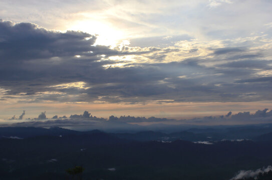 Dramatic Sunset Over Mountain Ridges. Layers of mountain ridges fade into the distance under a dramatic evening sky filled with glowing clouds.