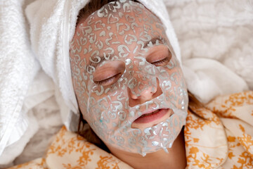 Close-up portrait of a beautiful girl with a face mask to improve and moisturize facial skin....