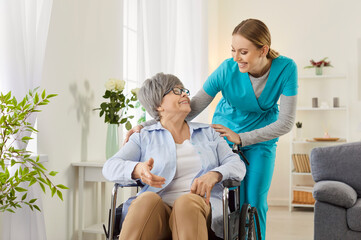 Professional female nurse gives help and support handicapped old lady in wheelchair, takes care of...