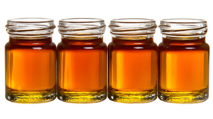 Four small glass jars filled with golden syrup or honey on a black background