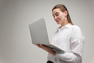 Focused Woman Engages With Laptop in Minimalist Workspace During Early Morning Hours, Showcasing Creativity and Determination