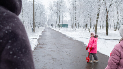 Grandmother with little girl granddaughter on snowy weather outdoors.