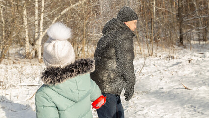 Playful family enjoying snowball fight in snowy winter park