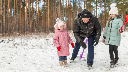 Little girls with her grandfather walk in a snowy forest, have fun together