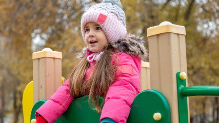 Little girl having fun on playground. Happy healthy little child climbing, swinging and sliding on...